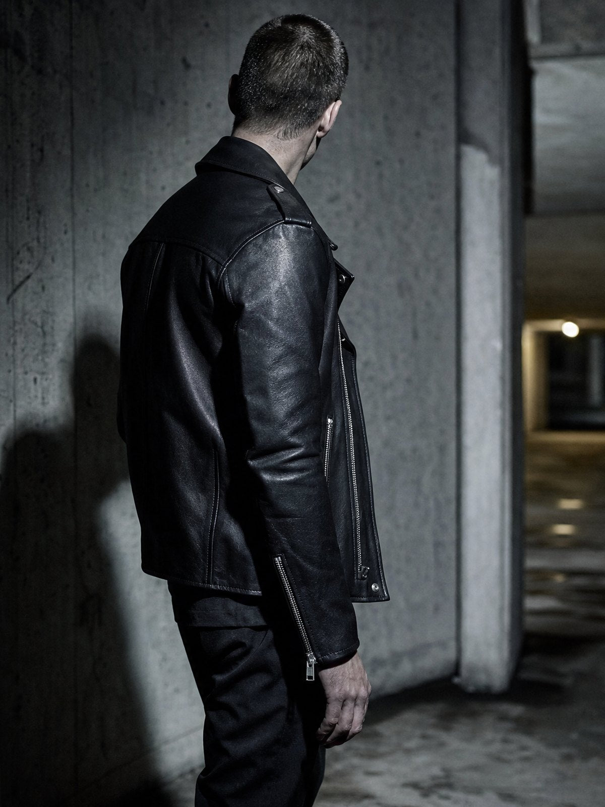 Man in a black ROCQERX faux leather biker jacket in a concrete underpass