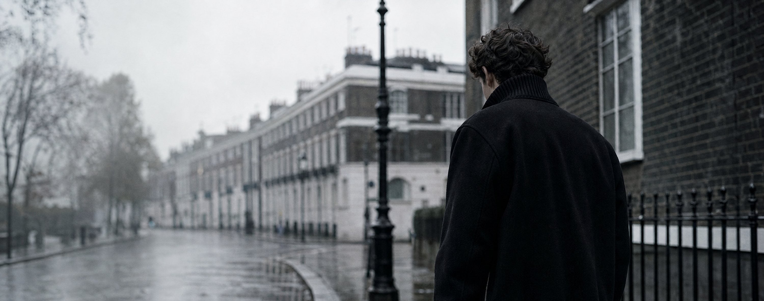 Man in a black ROCQERX wool-blend zip-up jacket on a wet London street